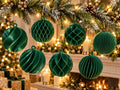 Emerald green 3D-printed geometric bauble ornaments with lattice, spiral, and ribbed patterns on a snowy garland