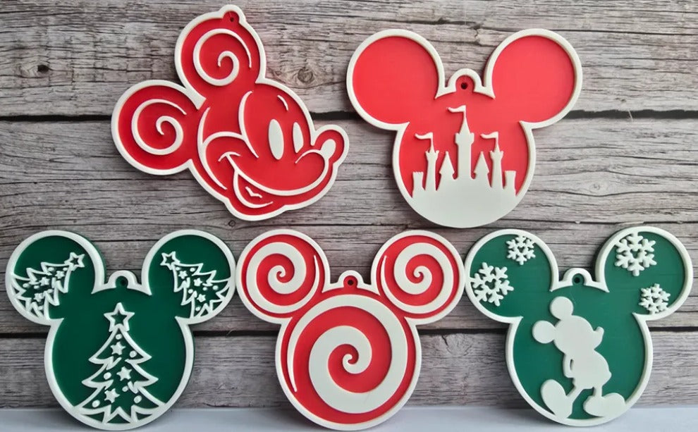 Five 3D-printed mouse-ear Christmas ornaments in red, green, and white: classic Mickey, castle, Christmas trees, peppermint swirl, and snowflakes