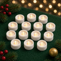 White flameless LED tealights with warm glowing bulbs on green felt with pine and berries