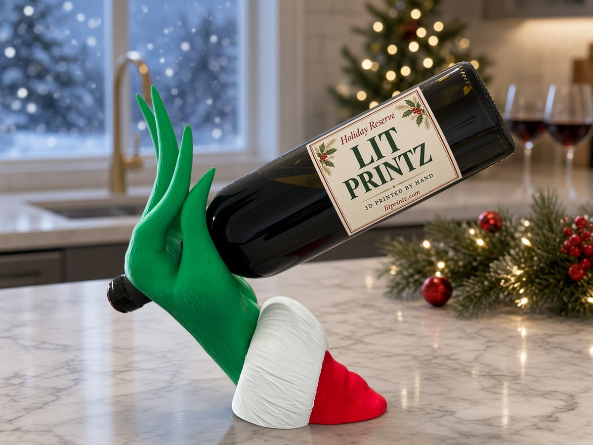 Grinch Hand Wine Bottle Holder on a marble kitchen counter by a snowy window, with holiday garland and wine glasses